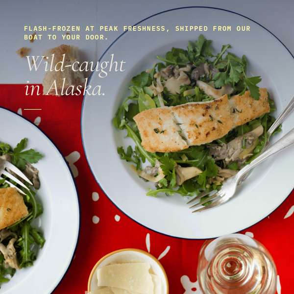 Pan-seared halibut fillet served on arugula and mushroom salad on a red tablecloth, overlaid headline Wild-caught in Alaska