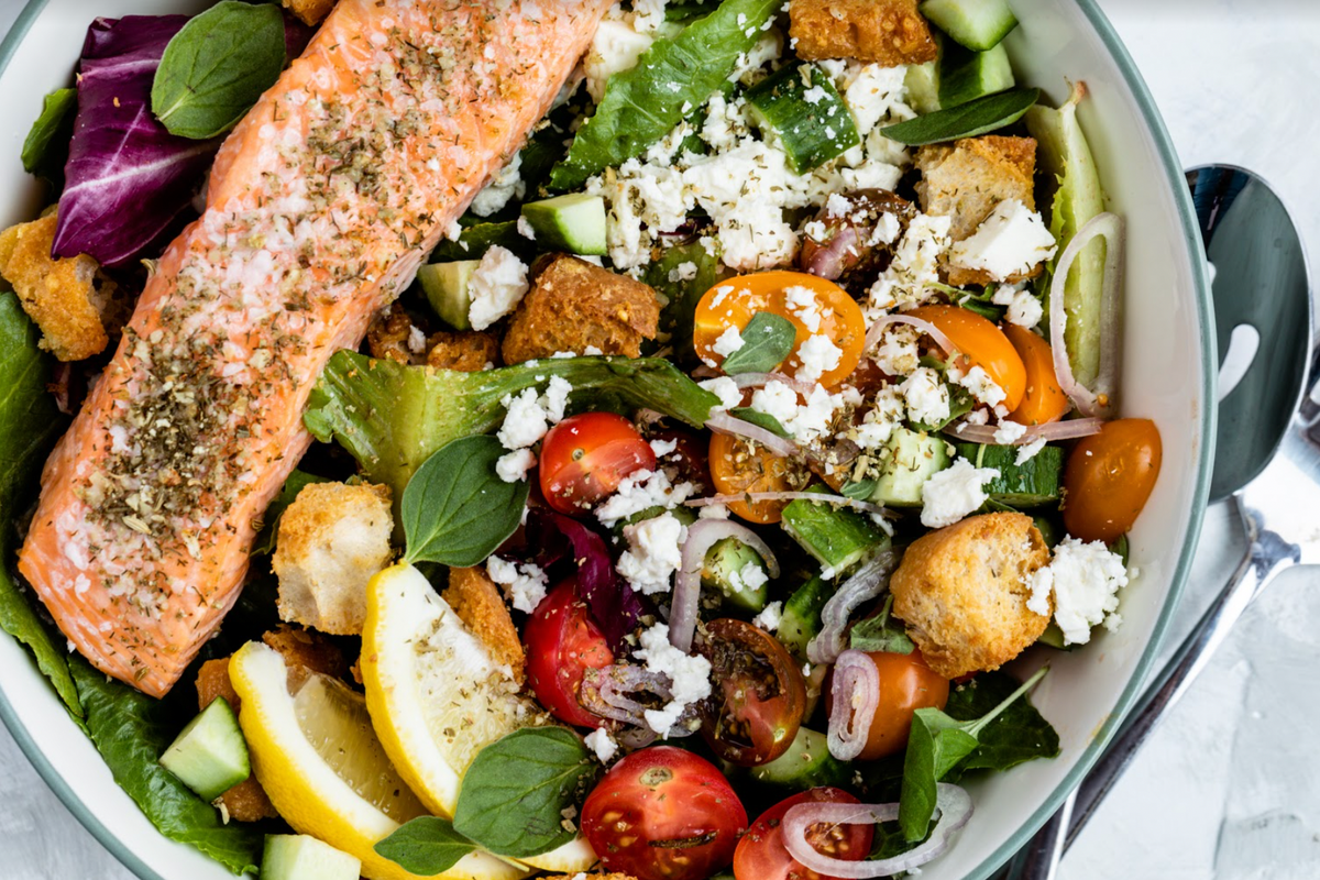 Cooked wild sockeye salmon fillet on mixed greens with cherry tomatoes, croutons, feta, cucumber and lemon wedge