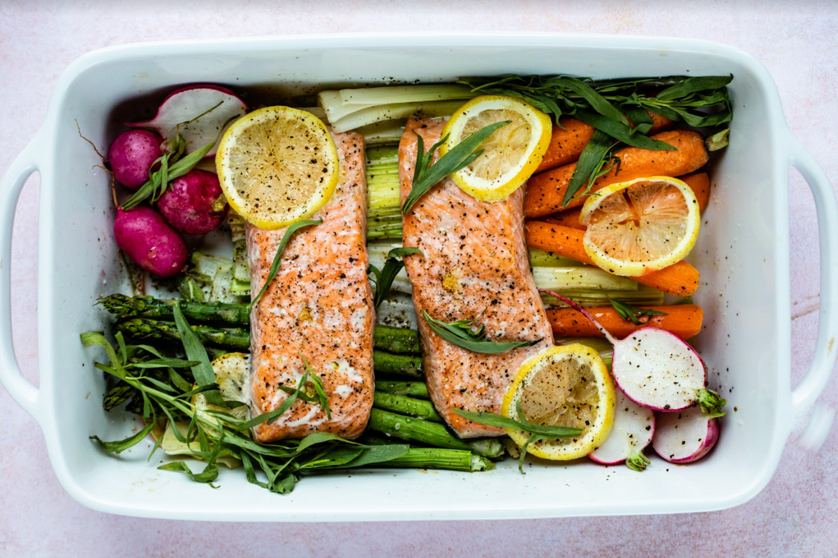 Alaskan wild salmon fillets with lemon, asparagus, carrots and radishes in white baking dish