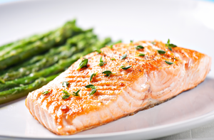 Seared salmon fillet served with roasted asparagus on a white plate