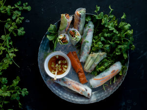 Spring rolls with salmon, fresh herbs, and dipping sauce on a decorative plate
