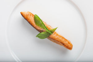 Top-down view of seared salmon fillet showcasing golden crust and pea garnish on a white plate