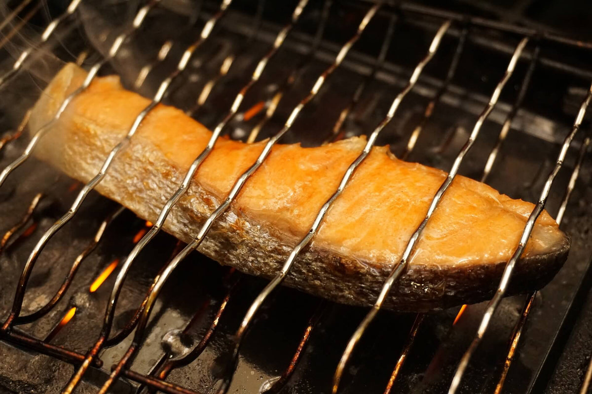 Alaskan salmon fillet broiling on a wire oven rack over glowing broiler flames