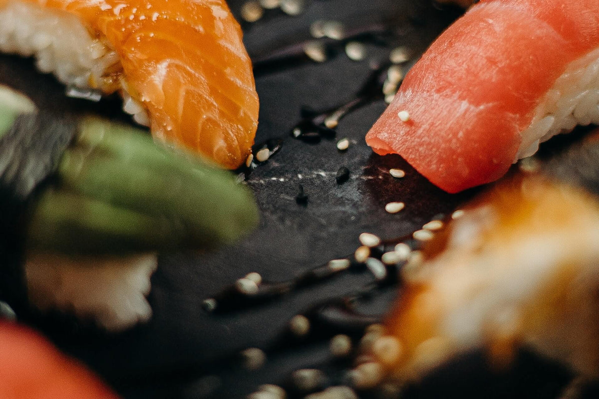 Close-up of salmon and tuna nigiri sashimi showcasing marbled salmon and tuna slices with sesame seeds on a dark slate
