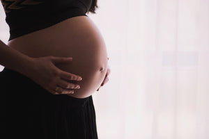 Pregnant woman's bare belly gently cradled by her hands