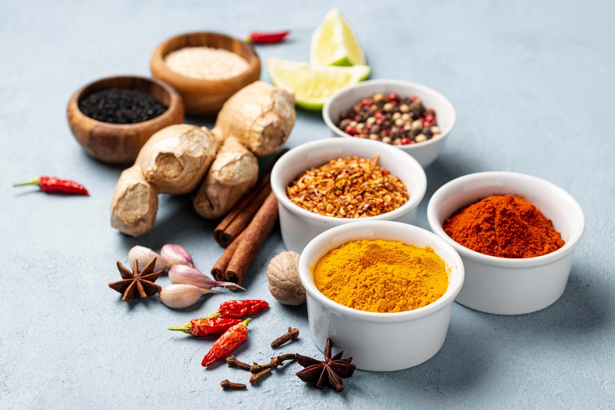 Assorted spices for seasoning fish: turmeric and chili in bowls, crushed red pepper, ginger, star anise, lime wedges