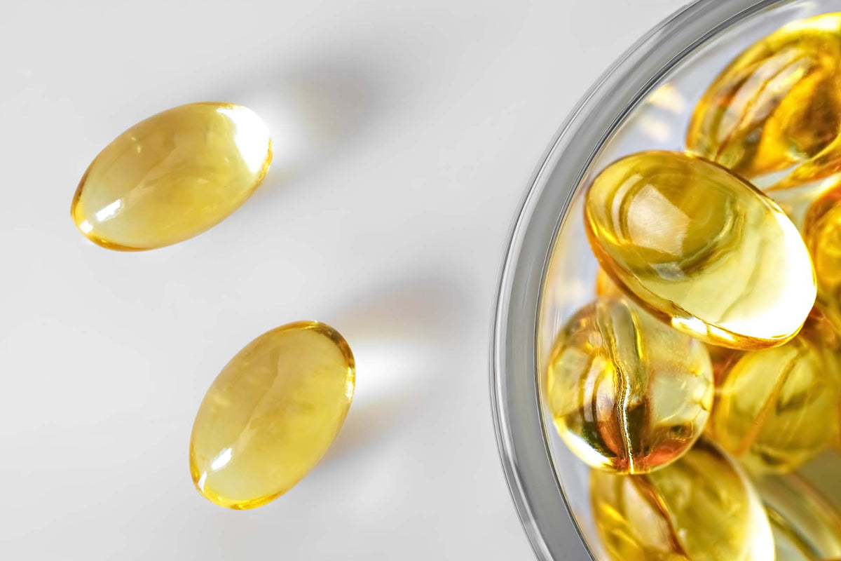 yellow translucent supplement capsules in a clear container and on a white surface