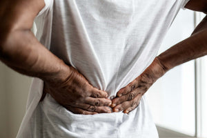 Person holding lower back, indicating possible back pain or discomfort