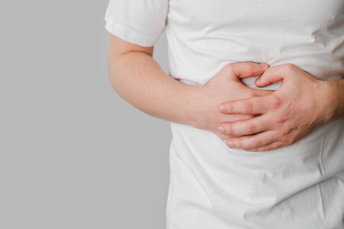 Person clutching lower abdomen with both hands suggesting abdominal pain or digestive discomfort