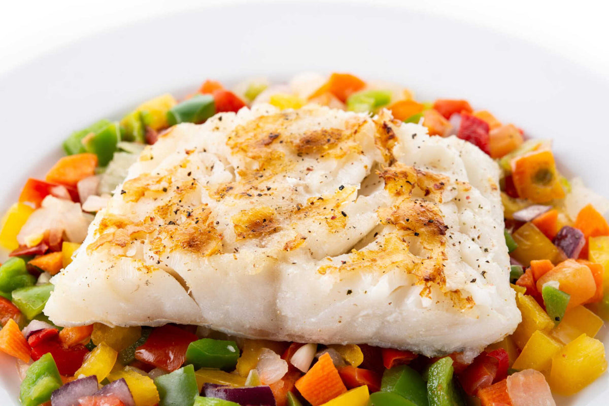 Pan-seared cod fillet resting on a bed of diced red, yellow and green bell peppers.