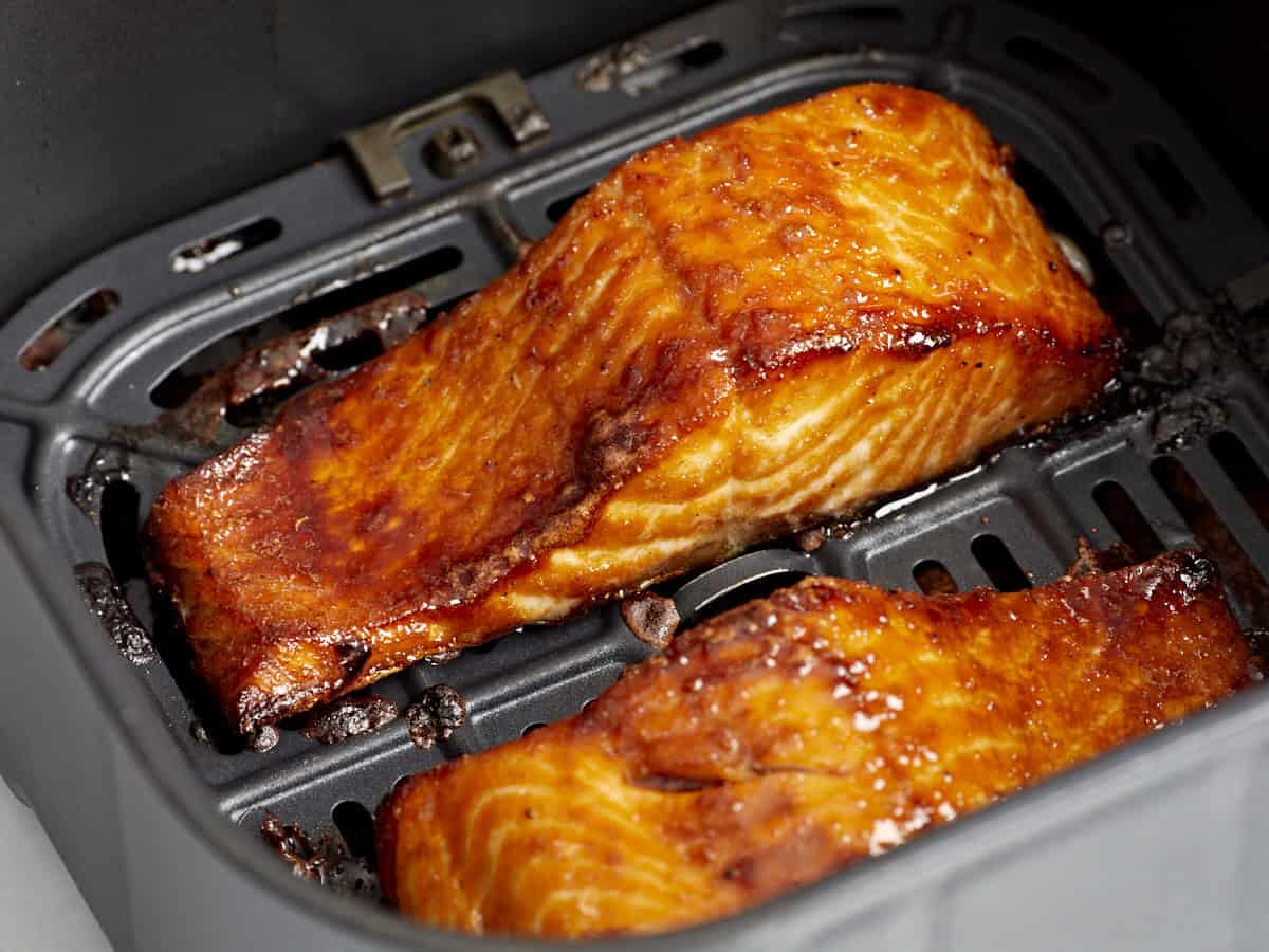 Two golden glazed Alaskan salmon fillets cooking in an air fryer basket