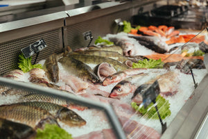 Fresh whole fish displayed on crushed ice at a market seafood counter