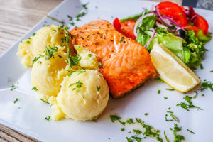 baked coho salmon in white plate with sides