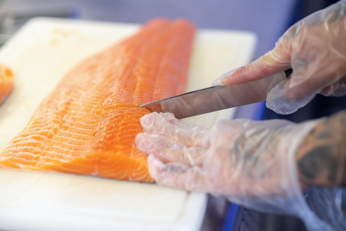 person cutting fish on a cutting board while selecting or buying fresh salmon for preparation