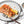 Cooked wild Alaskan king salmon fillet topped with toasted sliced almonds, cracked pepper, and a lemon wedge on a gray plate with a fork