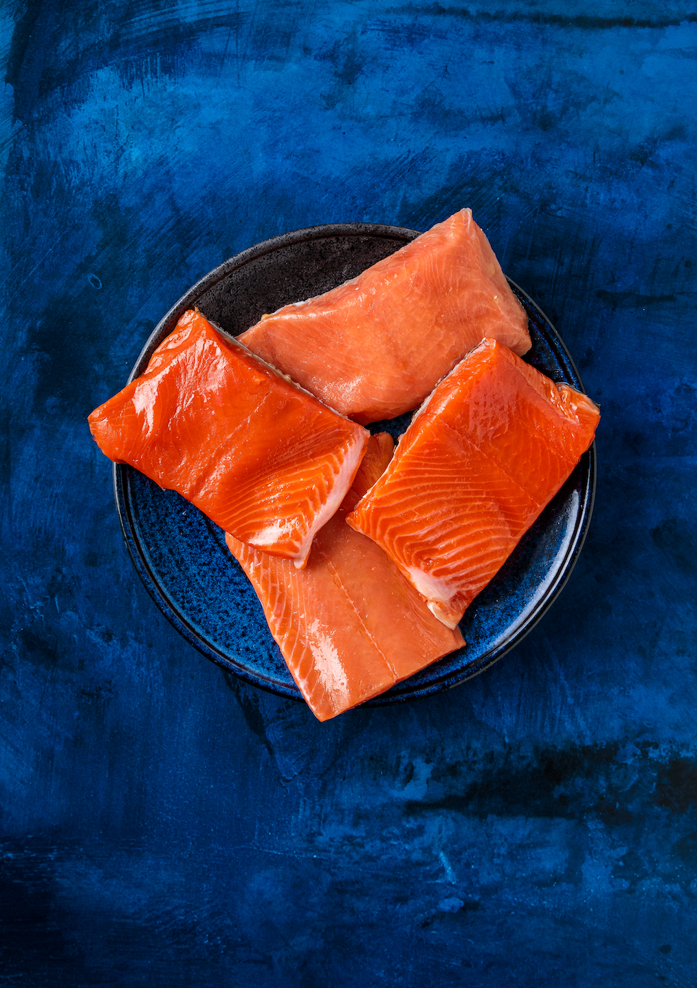Four portions of wild sockeye salmon on a dark plate