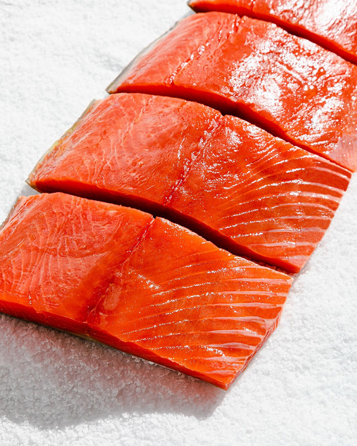 Fresh salmon fillets sliced and placed on coarse salt