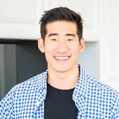 Kyle Lee Smiling wearing a blue checkered shirt and black t-shirt