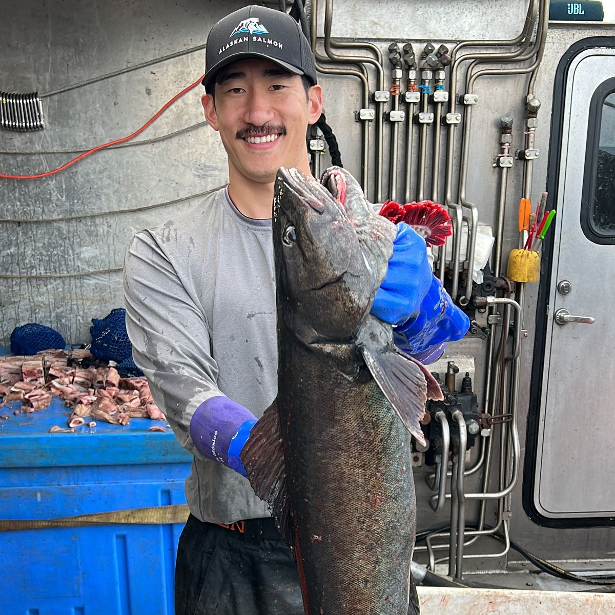 Kyle Lee, founder, on deck holding a large black cod