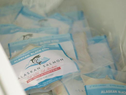 Vacuum-sealed fish portions with blue and white labels, piled in a cooler