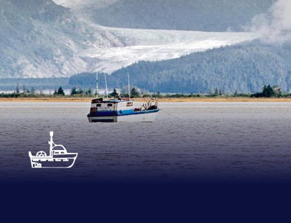 Fishing boat on calm water with forested mountains and glacier in the background